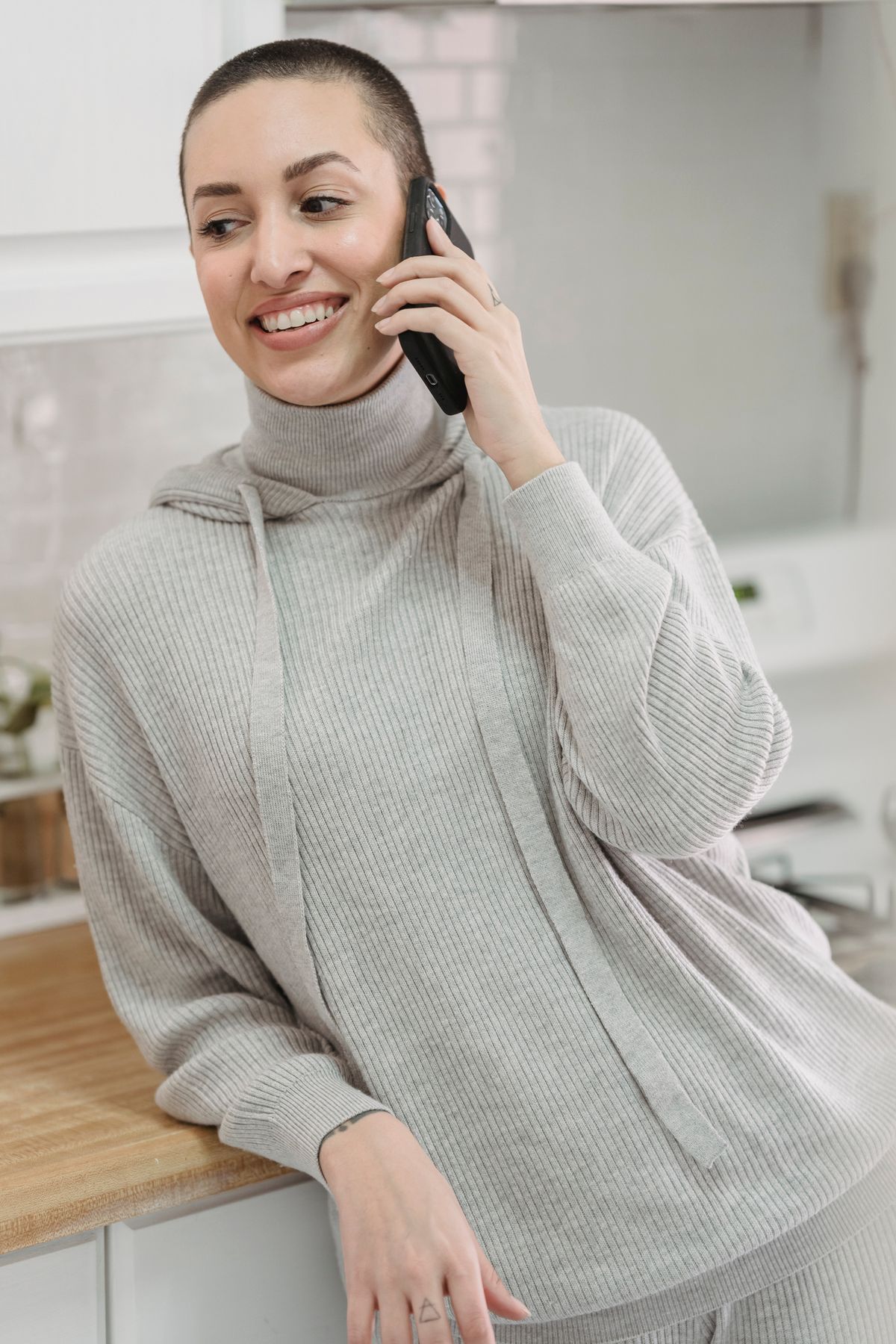 Opiekunka odpoczywa w domu ze spokojnym wyrazem twarzy podczas uspokajającej rozmowy telefonicznej